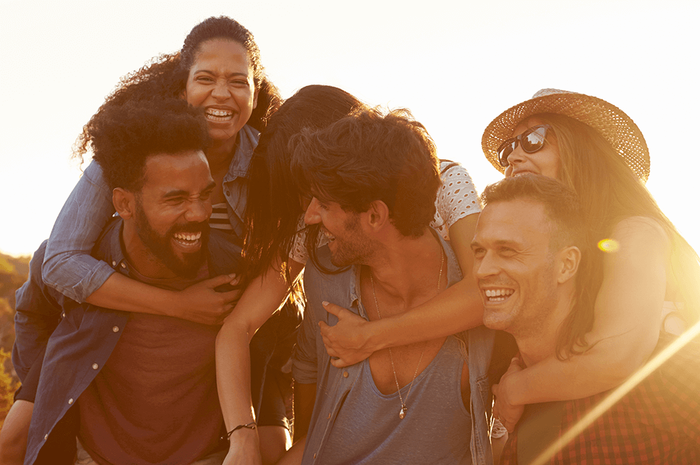 Grupo de amigos abrazados sonríen al aire libre