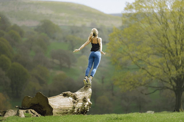 Mujer extiende sus manos y estira su cuerpo en la naturaleza