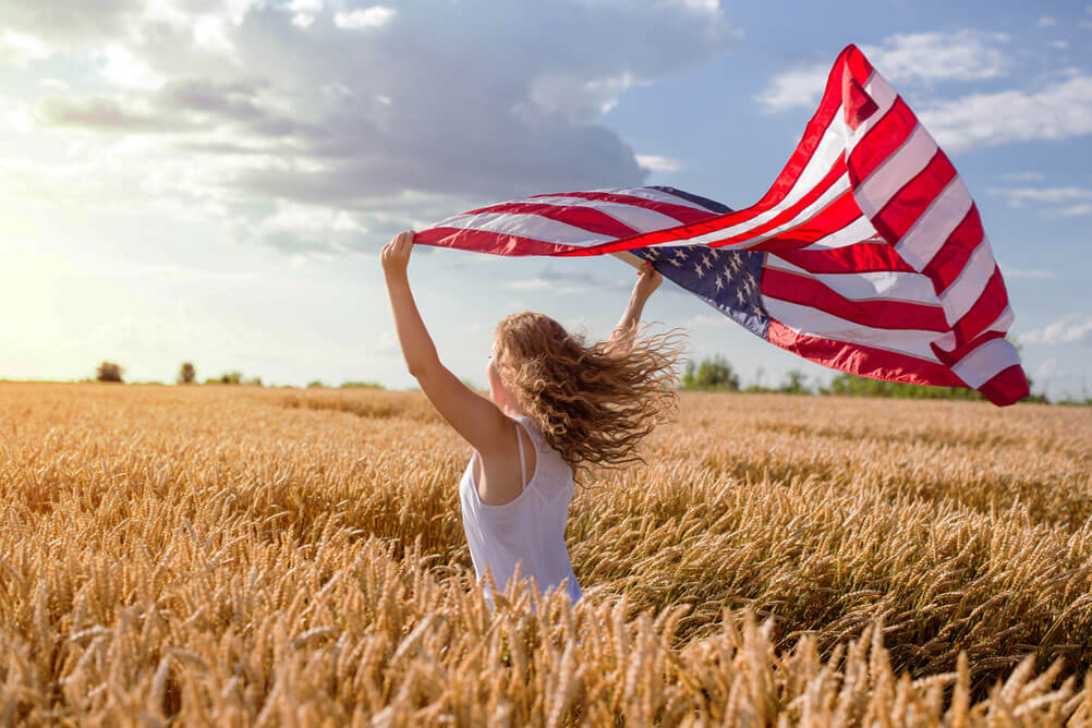 Mujer levanta bandera estadounidense y celebra el premio record de PowerBall