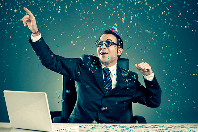 Hombre con corbata celebra en su escritorio feliz