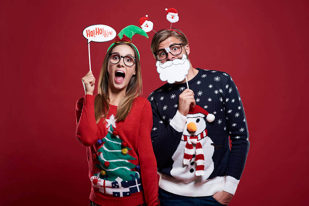 Hombre y mujer vestidos con suéters navideños