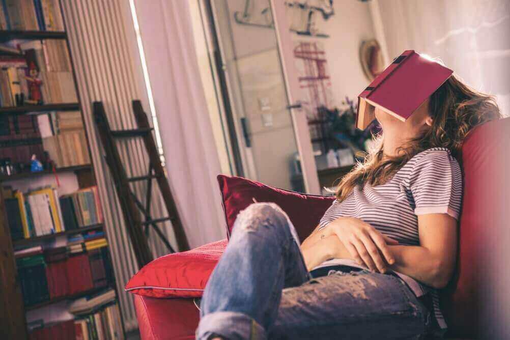 Mujer dormida en el sofá con un libro sobre su cabeza